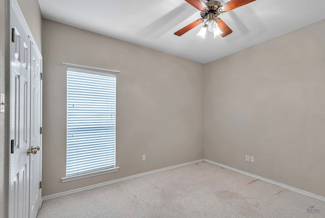 empty room featuring ceiling fan, plenty of natural light, baseboards, and light colored carpet