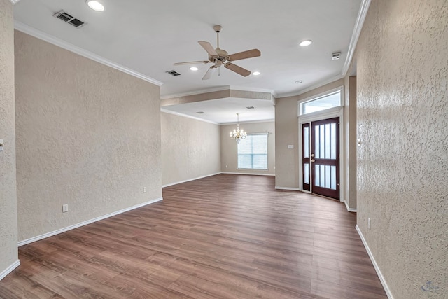 empty room with a textured wall, wood finished floors, visible vents, and baseboards