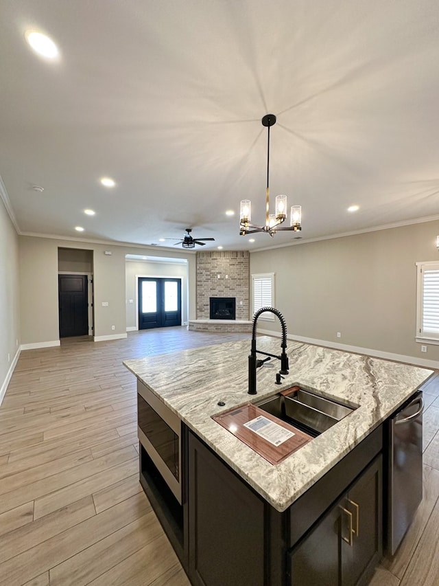 kitchen featuring stainless steel appliances, crown molding, sink, decorative light fixtures, and an island with sink