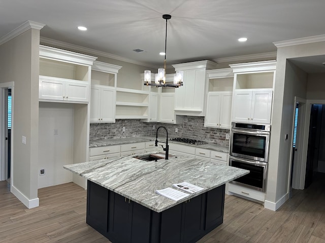 3624 Yorkshire Dr, Odessa, TX 79765 - kitchen featuring white cabinetry, light stone countertops, sink, decorative light fixtures, and a center island with sink