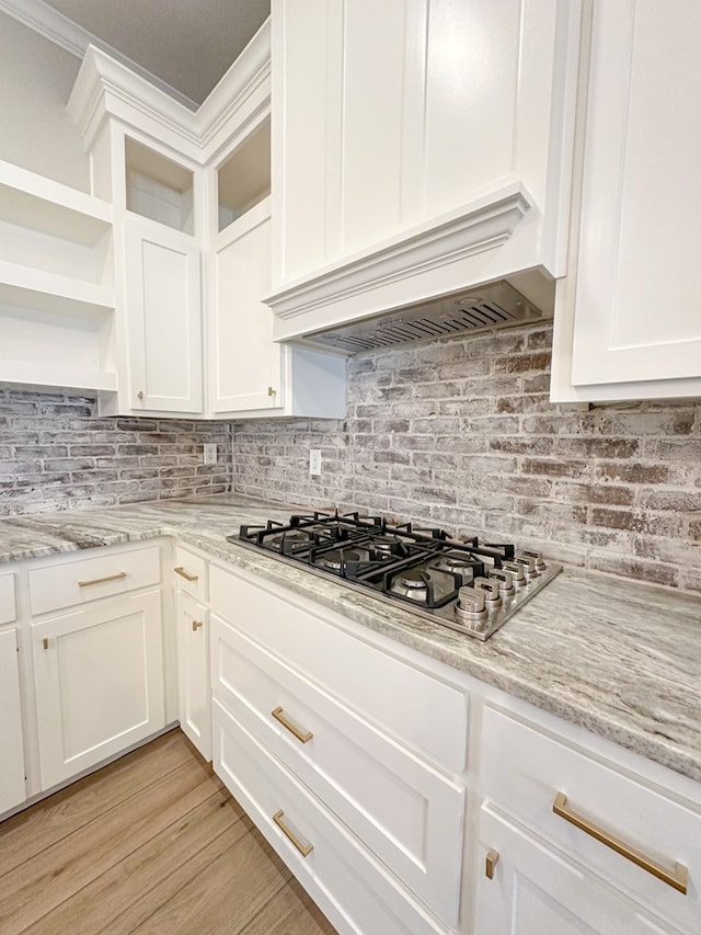 3624 Yorkshire Dr, Odessa, TX 79765 - kitchen with light stone countertops, backsplash, premium range hood, stainless steel gas cooktop, and white cabinets