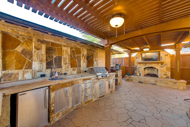 view of patio with a fireplace, an outdoor kitchen, grilling area, and sink