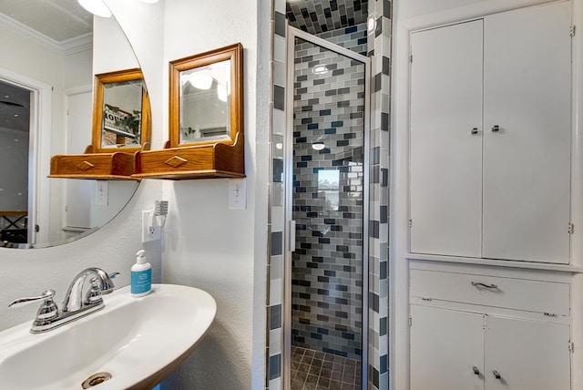 bathroom featuring a shower with door, crown molding, and sink