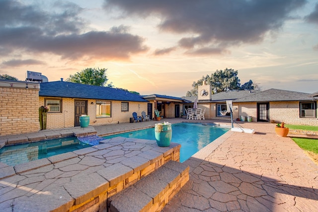 pool at dusk with a patio area