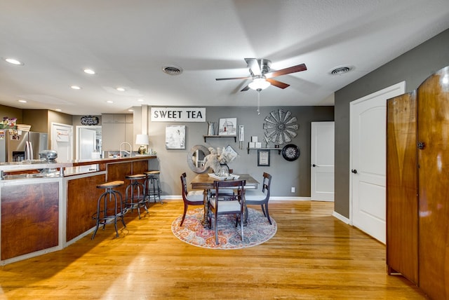 dining space with ceiling fan, light hardwood / wood-style flooring, and a textured ceiling