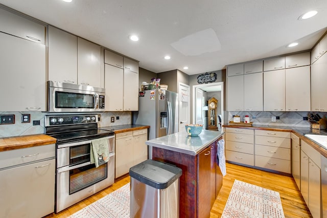 kitchen with light wood-type flooring, tasteful backsplash, a textured ceiling, stainless steel appliances, and a center island