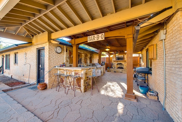 view of patio with area for grilling, grilling area, exterior bar, and exterior fireplace