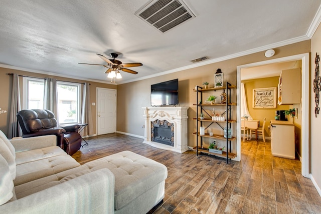 living room with hardwood / wood-style flooring, ceiling fan, crown molding, and a textured ceiling