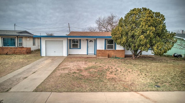 single story home featuring brick siding, a front lawn, concrete driveway, and an attached garage