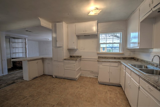 kitchen featuring a peninsula, white cabinets, light countertops, and a sink