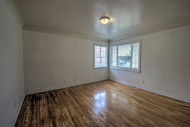 spare room featuring baseboards and hardwood / wood-style flooring