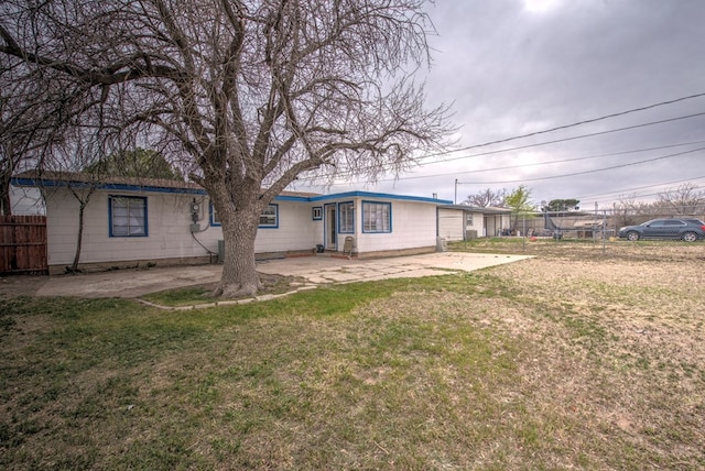 rear view of property featuring a yard, a patio area, and fence