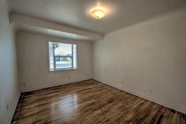 spare room featuring dark wood-style floors and baseboards