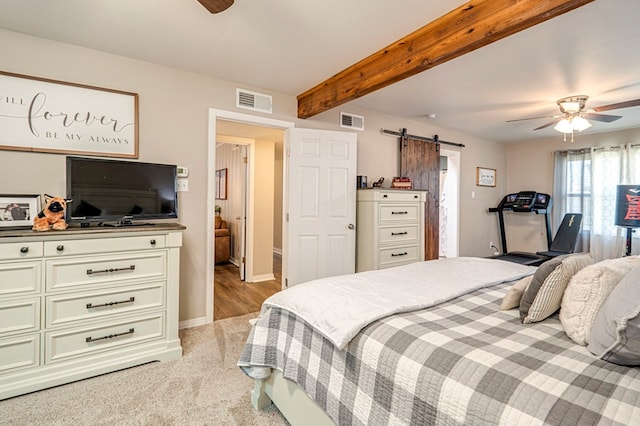 carpeted bedroom with beamed ceiling, a barn door, and ceiling fan