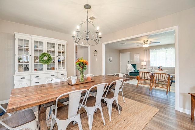 dining space featuring light hardwood / wood-style floors and ceiling fan with notable chandelier