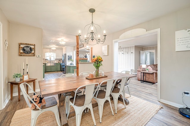 dining area with light hardwood / wood-style floors and an inviting chandelier