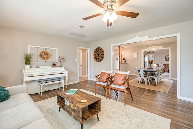 living room featuring ceiling fan with notable chandelier and hardwood / wood-style flooring