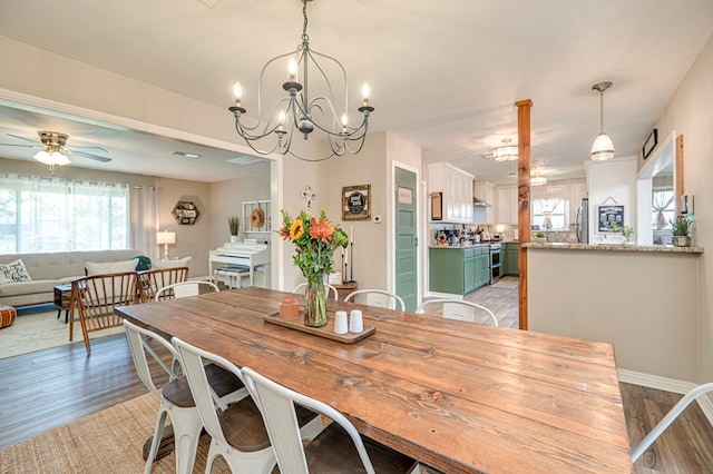 dining room with ceiling fan with notable chandelier and light hardwood / wood-style flooring