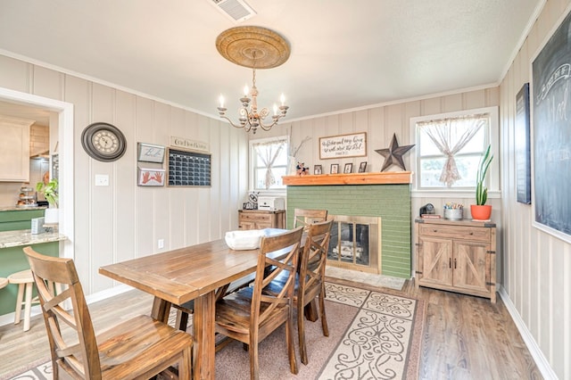 dining space with a fireplace, hardwood / wood-style flooring, a wealth of natural light, and crown molding