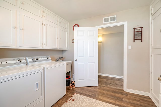 clothes washing area featuring cabinets, sink, hardwood / wood-style flooring, and washing machine and clothes dryer