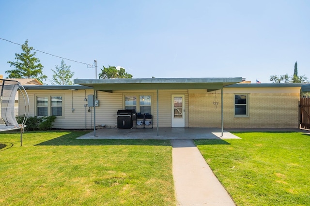 rear view of house featuring a lawn, a patio area, and a trampoline