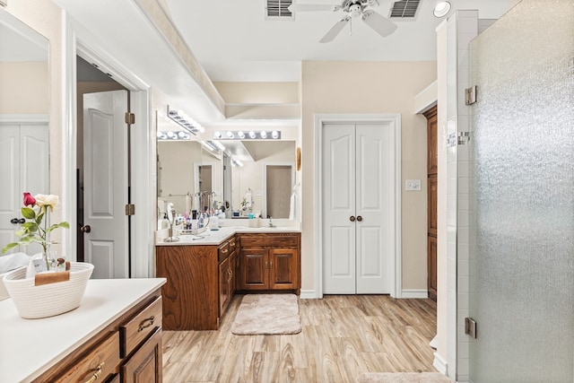 bathroom featuring wood-type flooring, vanity, an enclosed shower, and ceiling fan