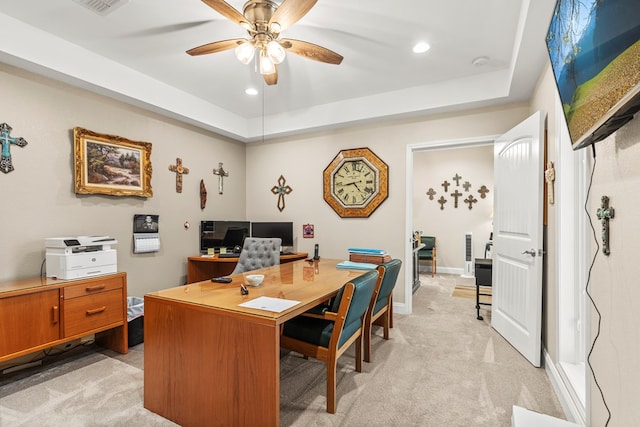 home office featuring light carpet, a raised ceiling, and ceiling fan