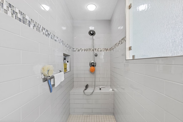 bathroom with a tile shower and a textured ceiling