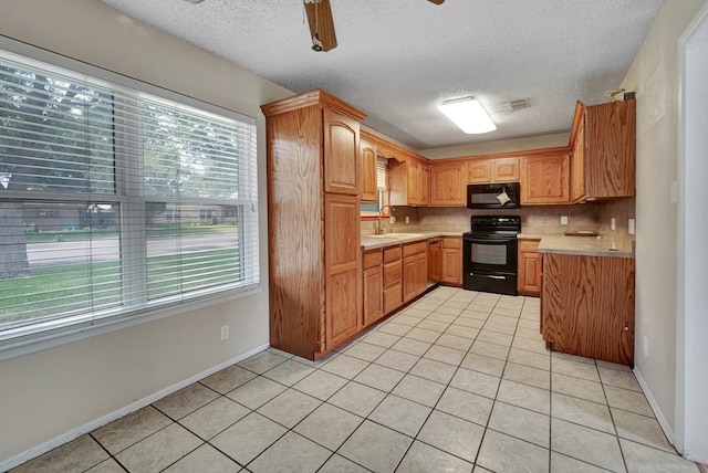 2408 Goddard Ct, Midland, TX 79705 - kitchen with black appliances, healthy amount of natural light, light countertops, light tile patterned flooring, and a textured ceiling