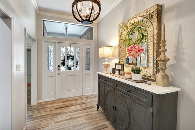 foyer entrance with crown molding, light wood-type flooring, and an inviting chandelier