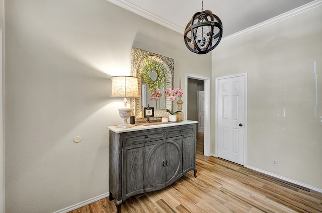interior space featuring light wood finished floors, a chandelier, baseboards, and ornamental molding