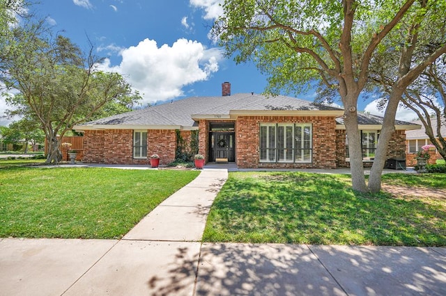view of front of property featuring a front lawn, a chimney, and brick siding