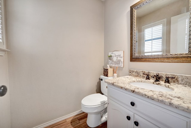 bathroom with toilet, baseboards, wood finished floors, and vanity