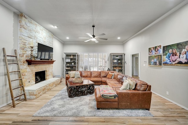 living area with ceiling fan, a stone fireplace, crown molding, and wood finished floors
