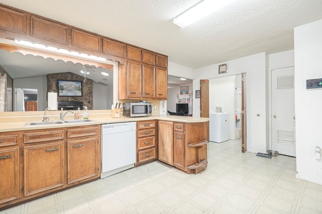 kitchen with sink, vaulted ceiling, white dishwasher, kitchen peninsula, and washer / clothes dryer