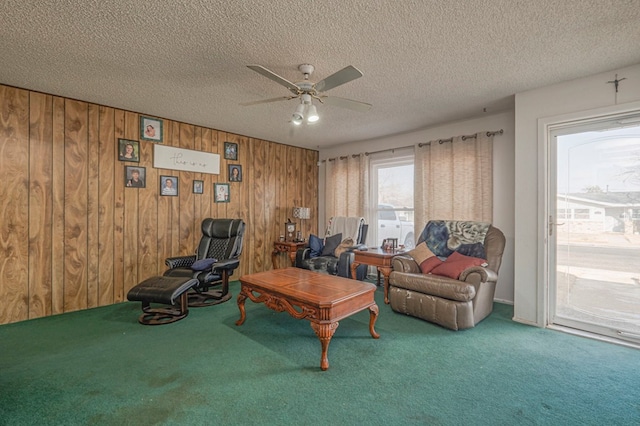 living room featuring ceiling fan, wooden walls, a textured ceiling, and carpet