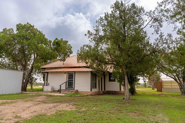 2950 Ranch Road 33, Big Spring, TX 79720 - back of house featuring entry steps, a lawn, an outbuilding, and a metal roof