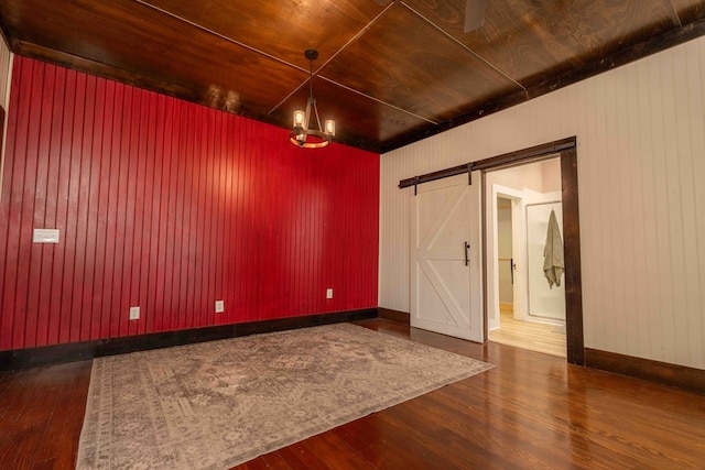 2950 Ranch Road 33, Big Spring, TX 79720 - unfurnished room with dark wood-type flooring, a barn door, a chandelier, and wood walls