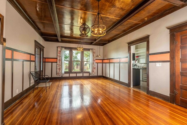 2950 Ranch Road 33, Big Spring, TX 79720 - unfurnished living room with wood-type flooring, a wood ceiling with exposed beams, a chandelier, a wainscoted wall, and a decorative wall
