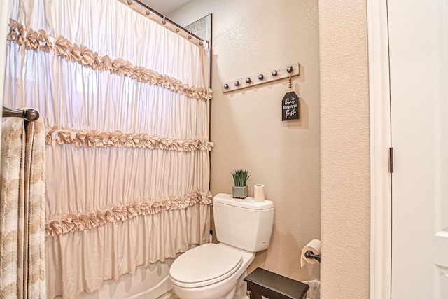 bathroom featuring toilet and a textured wall