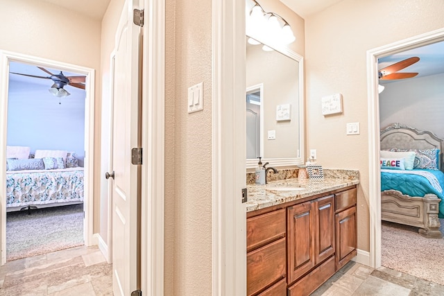 ensuite bathroom with baseboards, ceiling fan, ensuite bathroom, stone finish floor, and vanity