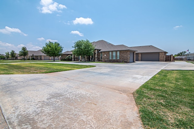 view of front of home with brick siding, an attached garage, fence, a front yard, and driveway