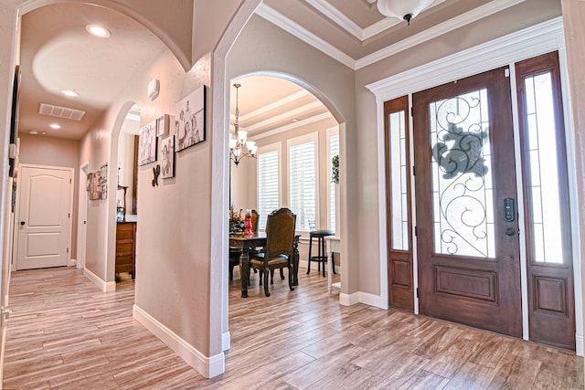 entrance foyer featuring arched walkways, light wood-style flooring, and crown molding