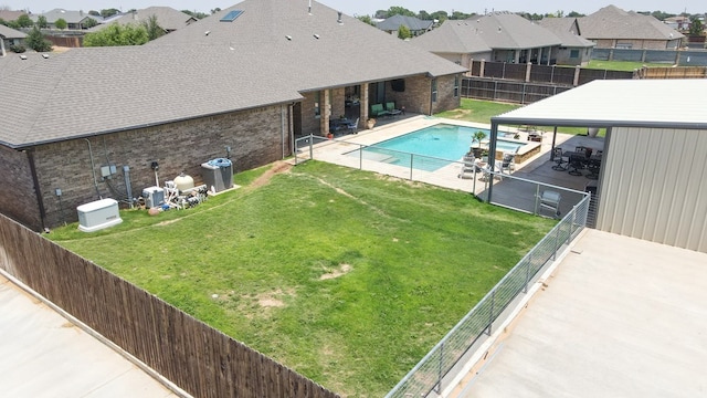 view of swimming pool featuring a lawn, a pool with connected hot tub, a patio, a fenced backyard, and a residential view