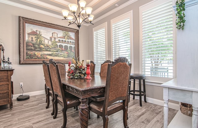 dining room featuring light wood-type flooring, baseboards, a notable chandelier, and ornamental molding