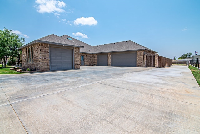 view of front of house with brick siding, driveway, a garage, and fence