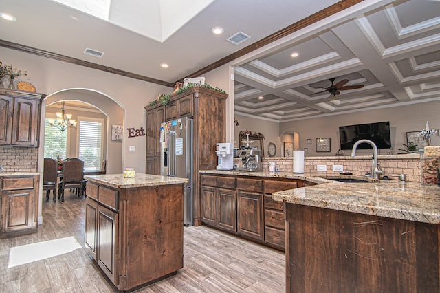 kitchen with high end fridge, arched walkways, backsplash, and a sink