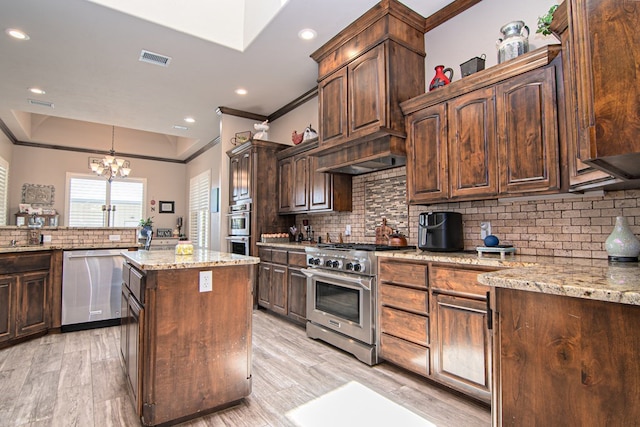 kitchen with visible vents, ornamental molding, stainless steel appliances, a raised ceiling, and a chandelier