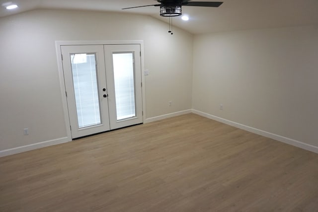 empty room with french doors, light wood-type flooring, vaulted ceiling, and plenty of natural light