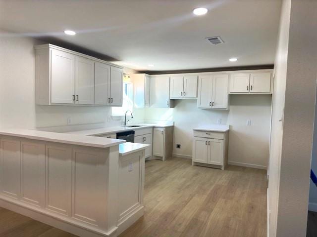 kitchen with kitchen peninsula, white cabinets, and light hardwood / wood-style floors